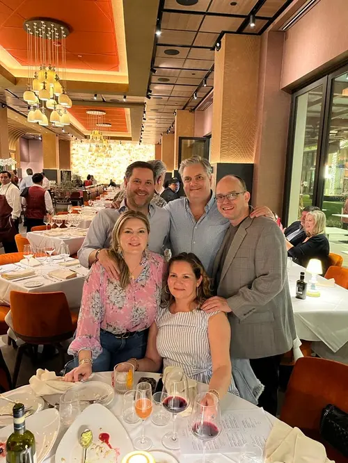 Esteban Rey posa con amigos en una cena, siempre con su toque de naranja.
