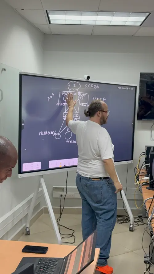 Esteban Rey explica algo con su característica camiseta naranja en una oficina.