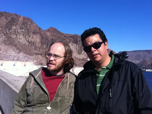 Esteban Rey y un amigo en una represa, vestidos con ropa de invierno.